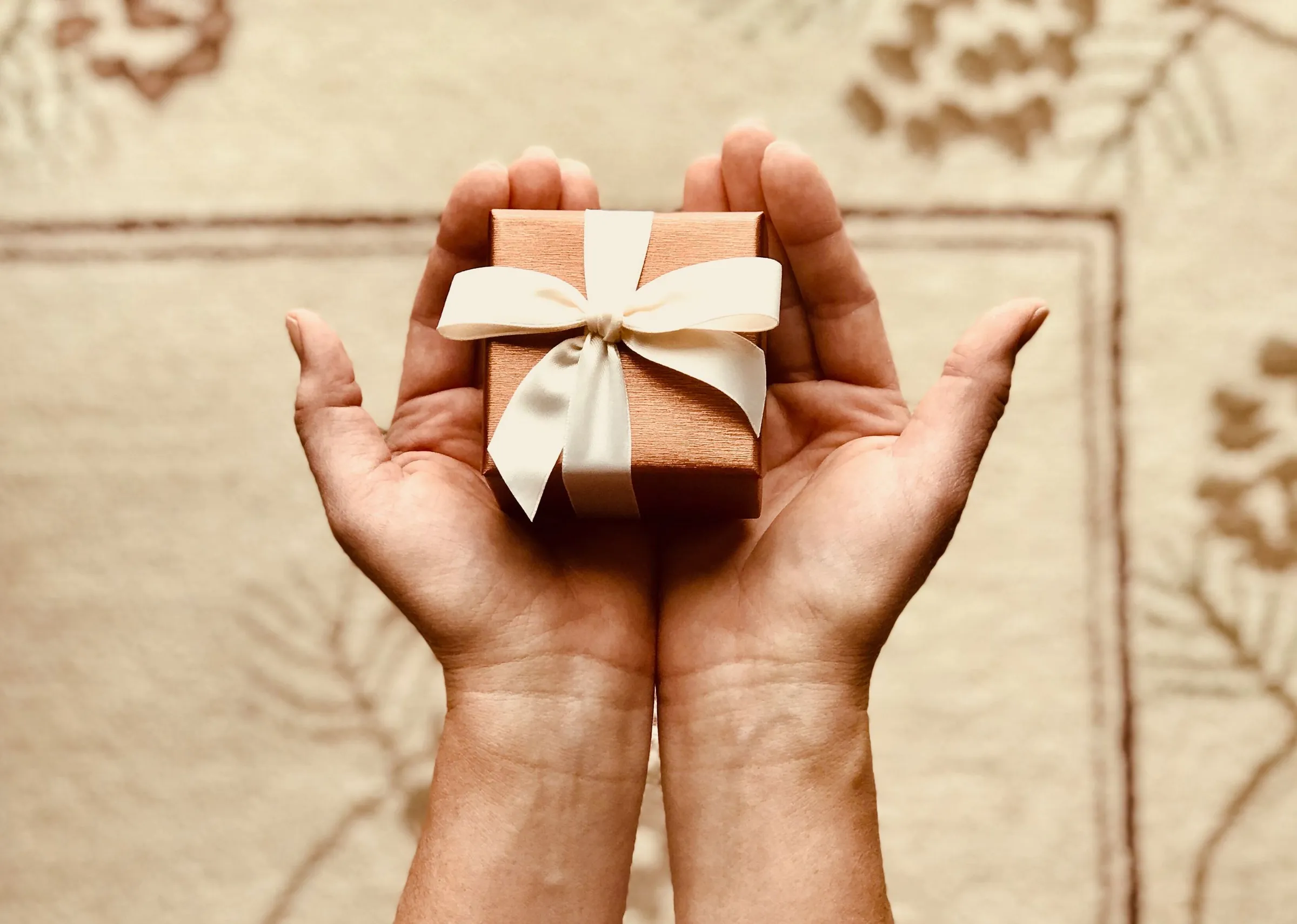 Des mains qui tendent un petit paquet cadeau